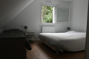 a white bedroom with a bed and a window at La maison de Qui miac in Quimiac