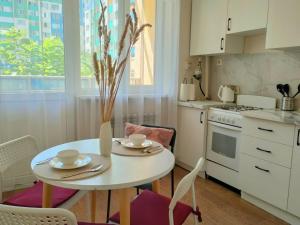 a kitchen with a white table and chairs and a stove at ЖК Шугыла Apartment in Shugyla