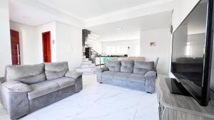 a living room with two couches and a tv at Triplex com piscina e área gourmet in Guaratuba