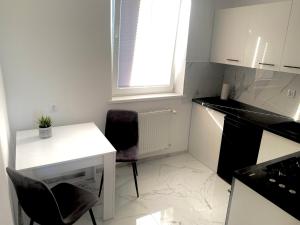 a small kitchen with a white table and chairs at Apartament nad morzem Darłowo Młyńska in Darłowo
