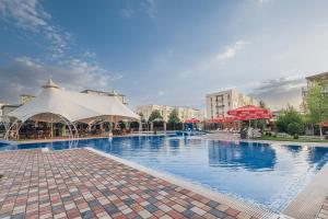 a large swimming pool with tables and white umbrellas at Grand Fergana Hotel in Fergana