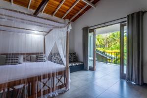 a bedroom with a bed and a balcony at 18 Villa in Hikkaduwa