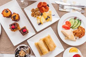 four white plates with different types of food on them at Grand Fergana Hotel in Fergana