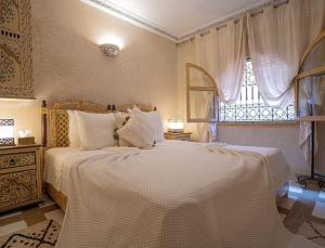una camera da letto con un grande letto bianco con una finestra di Authentic house in the old Medina of Marrakech a Marrakech