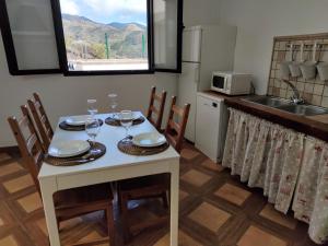 een keuken met een tafel en stoelen met wijnglazen bij Casa Cueva Ca Maruca in Gáldar