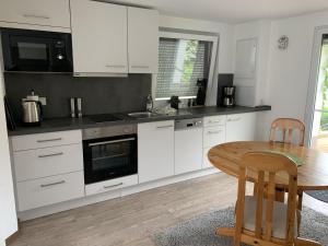 Una cocina con gabinetes blancos y una mesa de madera. en Ferienhaus Johanna, en Schmalkalden