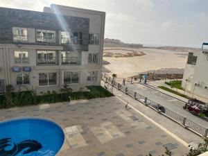ein Gebäude mit einem Pool neben einem Strand in der Unterkunft Elite North coast Seaview resort in El-Alamein