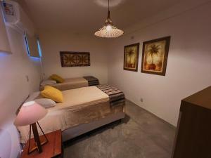 a bedroom with two beds and a light fixture at Suítes Arraial in Arraial d'Ajuda