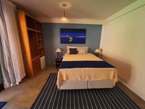 a bedroom with a bed and a blue wall at Suítes Arraial in Arraial d'Ajuda