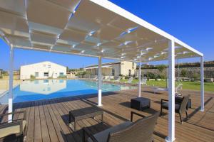 a white pergola over a deck with a swimming pool at Petrantica in Marina di Ragusa