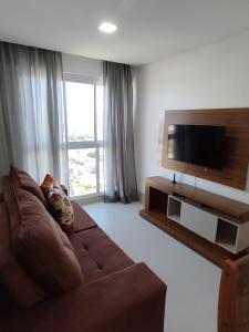 a living room with a brown couch and a flat screen tv at Ap 805 com suíte Edifício City House in Barreiras