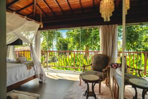 a bedroom with a bed and a chair and a balcony at Pousada Villa Tainá - Arraial d'Ajuda, Bahia in Arraial d'Ajuda