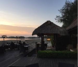 un restaurante con mesas y una sombrilla de paja en Tasik Dedap, en Sepang