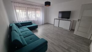 Una sala de estar con un sofá azul y un televisor de pantalla plana. en Oscar Apartment, en Ujazd