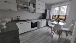 a kitchen with white cabinets and a table and chairs at Oscar Apartment in Ujazd +2 photos
