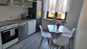 cocina con mesa, mesa blanca y sillas en Oscar Apartment, en Ujazd