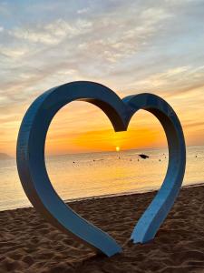 une sculpture de cœur sur la plage avec le coucher du soleil dans l'établissement classy new 2 bedrooms 2 bathrooms apartment at Domina coral bay sea view with everything you need, à Charm el-Cheikh