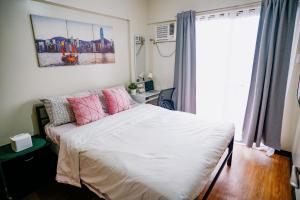 a bedroom with a bed with pink pillows and a window at Eves Urban Haven in Manila