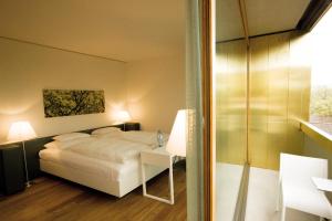 um quarto de hotel com uma cama, uma mesa e uma porta de vidro em Hotel am See em Hard