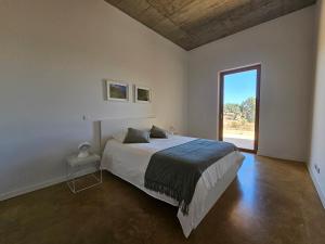 ein Schlafzimmer mit einem Bett und einem großen Fenster in der Unterkunft Casa de Mosqueirões in Santa Margarida da Serra + 36 Fotos
