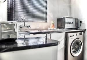 a kitchen with a sink and a washing machine at Lelwapa Stay in Gaborone