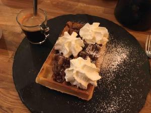 ein schwarzer Teller mit Waffeln mit Butter und Sirup in der Unterkunft Chalet de montagnes in Campan