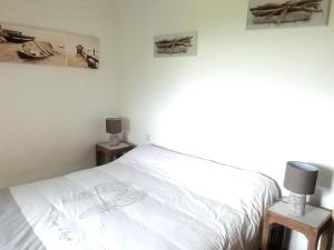 Un dormitorio con una cama blanca y dos mesitas de noche. en la maison de Marie, en Beaumont-les-Autels