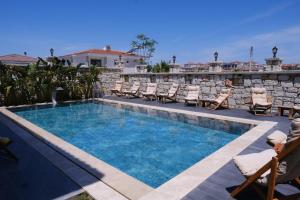 a swimming pool with chaise lounges and chairs around it at Marrakesh Alaçatı in Ildır