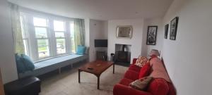 a living room with a red couch and a table at Cippinstone in Newport Pembrokeshire