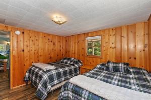 zwei Betten in einem Zimmer mit Holzwänden in der Unterkunft Applewood Cabins & Guest Cabin Near the Village in Big Bear Lake