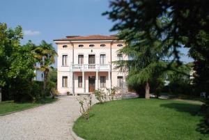 uma grande casa branca com uma varanda no topo de um quintal em B&B Villa Romano em Treviso