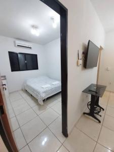 a room with a bed and a tv and a mirror at Casa de Temporada Uberaba com Piscina Aquecida in Uberaba +19 photos