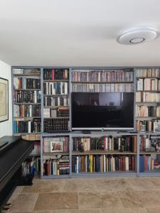 a entertainment center filled with books and a flat screen tv at Chambre du paille en queue in Bergerac