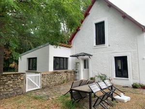 a table and chairs in front of a white house at Le Cottage du Domaine in Boissettes