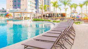 Salinas Exclusive Resort في سالينوبوليس: مسبح في منتجع فيه كراسي للاستلقاء والنخيل