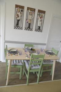 a table with green chairs and a table with plates and dishes at Renovated French Country House for Six - A Home for Your Next Holiday in Hercé