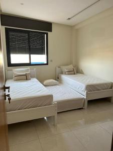 two beds in a room with a window at Nour Beach 8 Cabo in Martil +25 photos