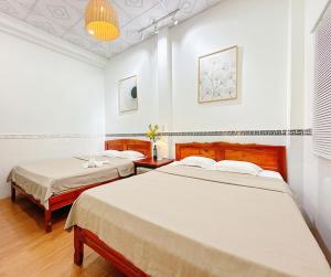 two beds in a room with white walls at Quoc Dinh Guest House in Mui Ne