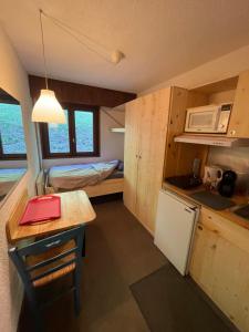 a small kitchen with a table and a refrigerator at Studio 1 personne Hedi 4 in Megève