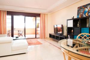 a living room with a white couch and a tv at Luxury apartment with sea views, golf, gym, spa, 7 pools in Ojén