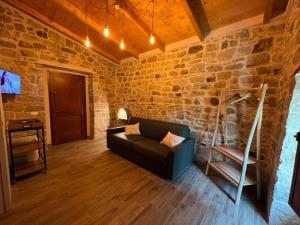 a living room with a couch and a stone wall at Il Melograno in Civita Campomarano