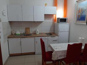 a kitchen with white cabinets and a table with chairs at Guest house Renata 2 in Zadar