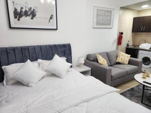 Al Ḩamīdīyahにあるfurnished studio for rent Ajmanの白いベッドとソファのある寝室