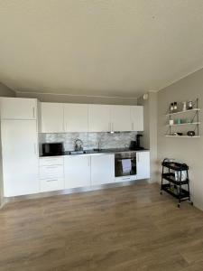 an empty kitchen with white cabinets and a sink at Comfy flat in Kópavogur in Reykjavík