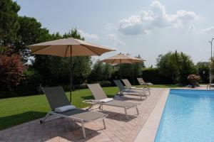 una fila di sedie e ombrelloni accanto a una piscina di VILLA ELENA a Moniga Altre 97 foto