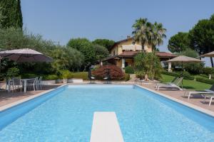 una piscina con sedie e ombrelloni accanto a una casa di VILLA ELENA a Moniga