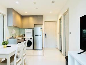 een keuken met een koelkast en een tafel bij Rhythm sukhumvit 36 two bedrooms in Bangkok