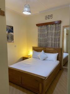 a bedroom with a bed with white sheets and a window at Casa Mianzini in Arusha