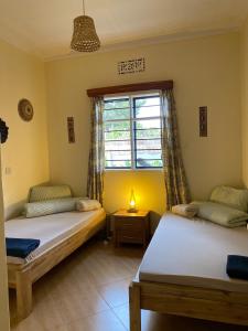 two beds in a room with a window at Casa Mianzini in Arusha