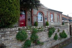 a brick house with a brick retaining wall with a red door at The Old Magistrates Court in Melbourn